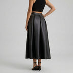 Black leather skirt worn by a person on a gray background