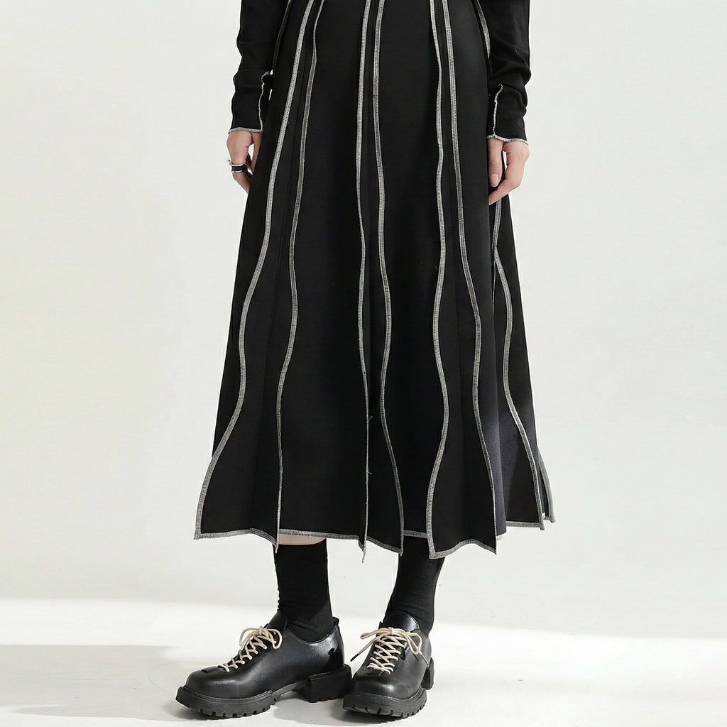 Person wearing a long black dress with white stripes on a white background