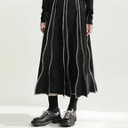 Person wearing a long black dress with white stripes on a white background