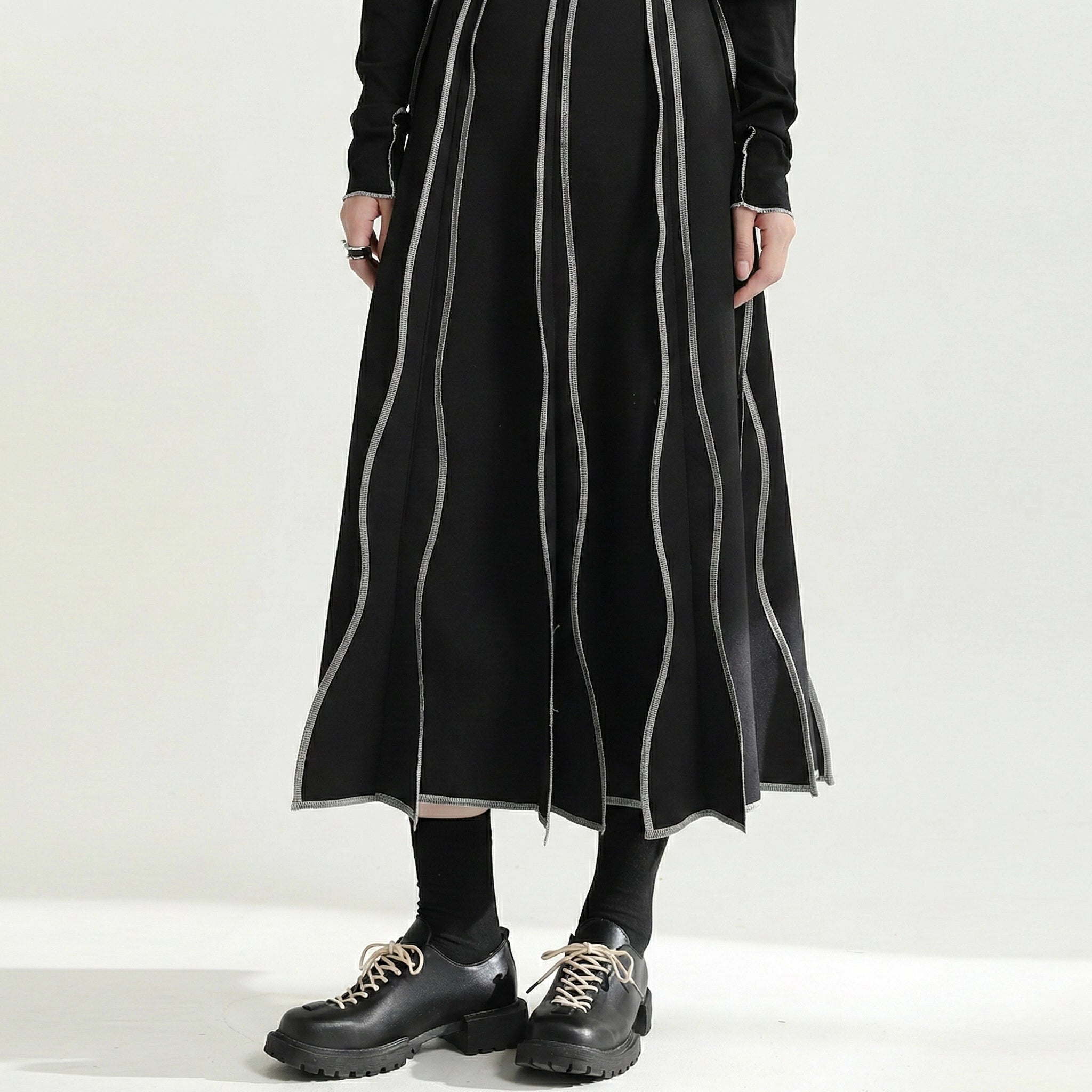 Person wearing a long black dress with white stripes on a white background