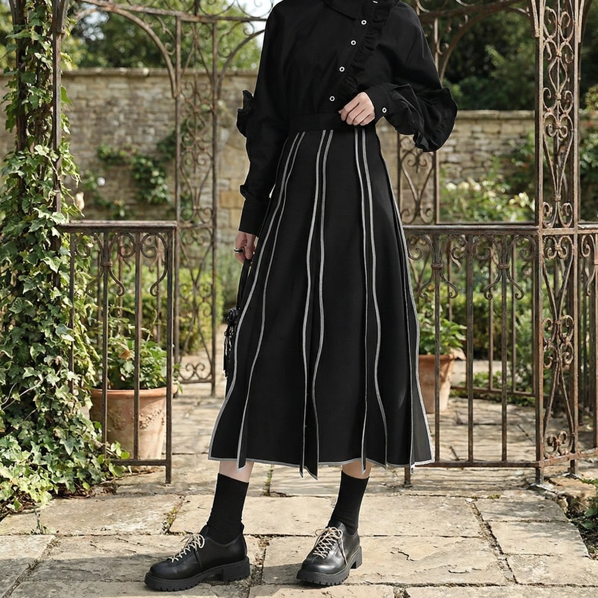 Person wearing a black outfit with white stripes in an outdoor setting