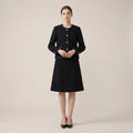 Woman wearing a black coat and skirt set on a beige background