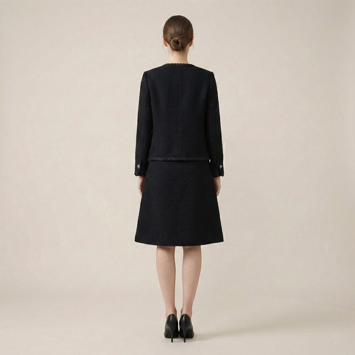 Person wearing a black outfit on a beige background