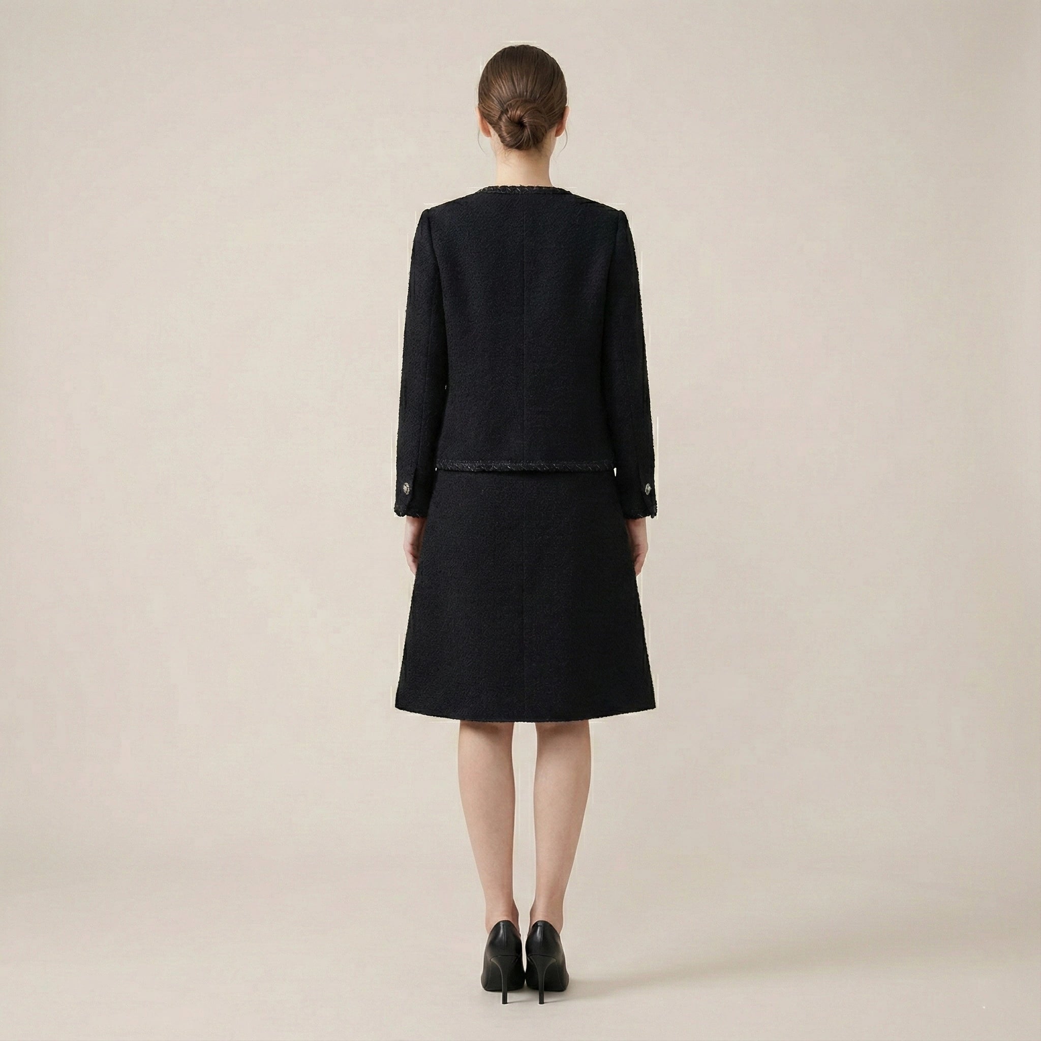 Person wearing a black outfit on a beige background