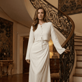 Woman in a white dress standing on a staircase in an elegant interior setting