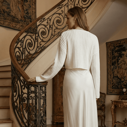 Woman in a white outfit standing on a staircase in an elegant interior setting
