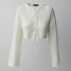 White ribbed knit cardigan with long sleeves on a gray background