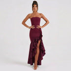 Woman wearing a strapless burgundy dress with ruffle details on a white background