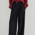 Black wide-leg pants worn with a red knitted sweater on a light gray background