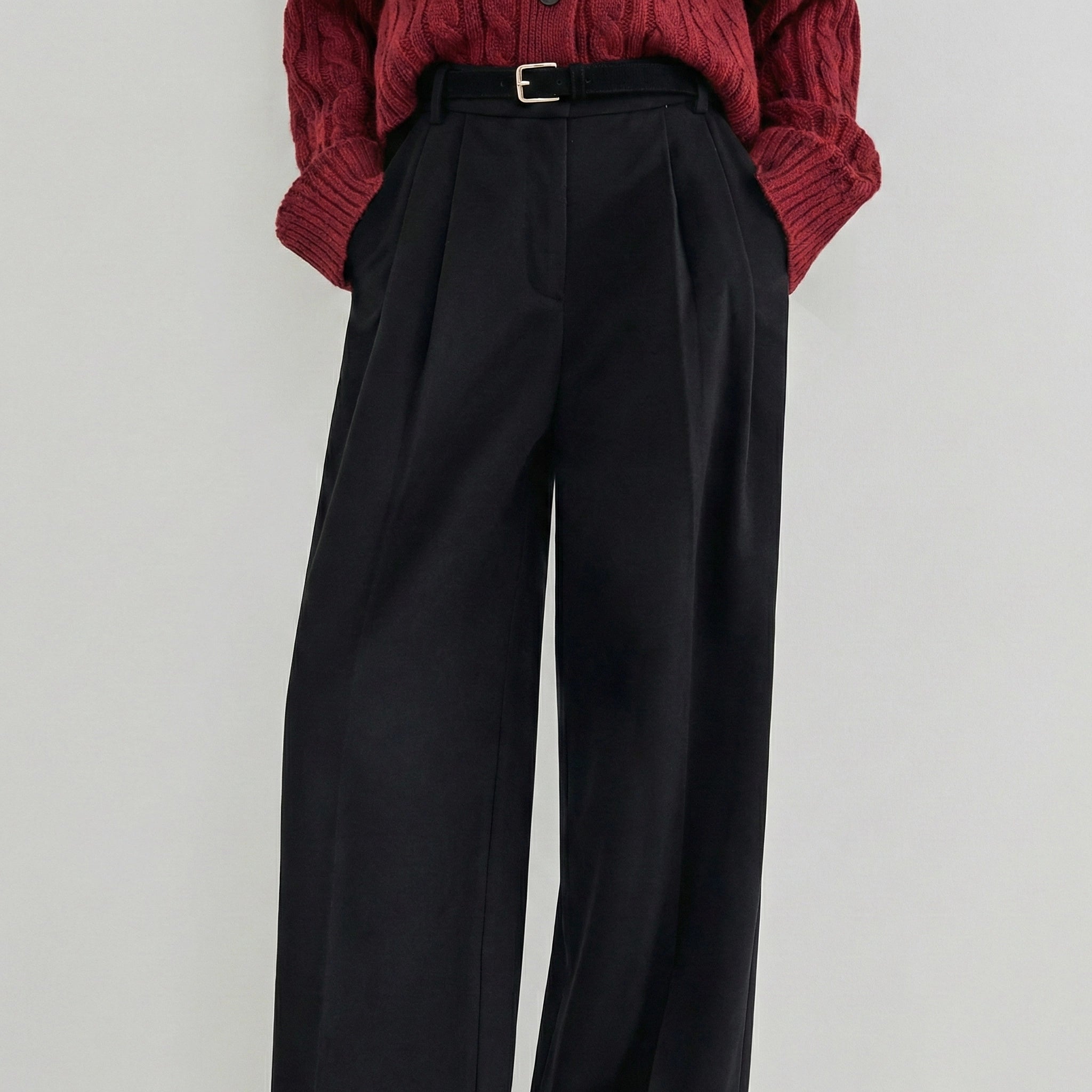 Black wide-leg pants worn with a red knitted sweater on a light gray background
