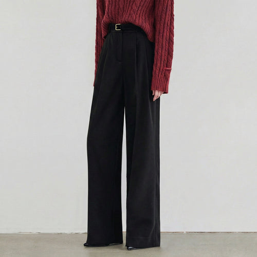 Person wearing a red sweater and black wide-leg pants against a plain background