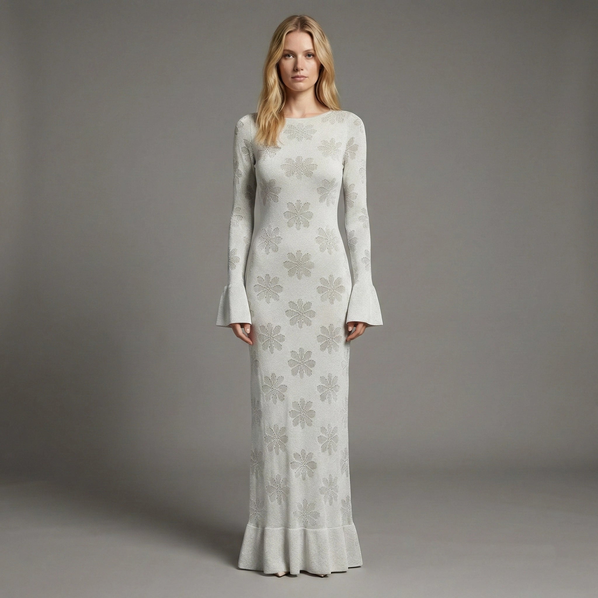 Woman wearing a long, light gray dress with floral patterns against a gray background