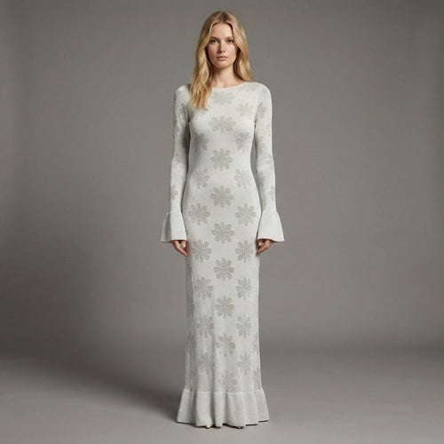 Woman wearing a long, light gray dress with floral patterns against a gray background