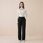 Woman wearing a white long-sleeve top and black pants on a beige background