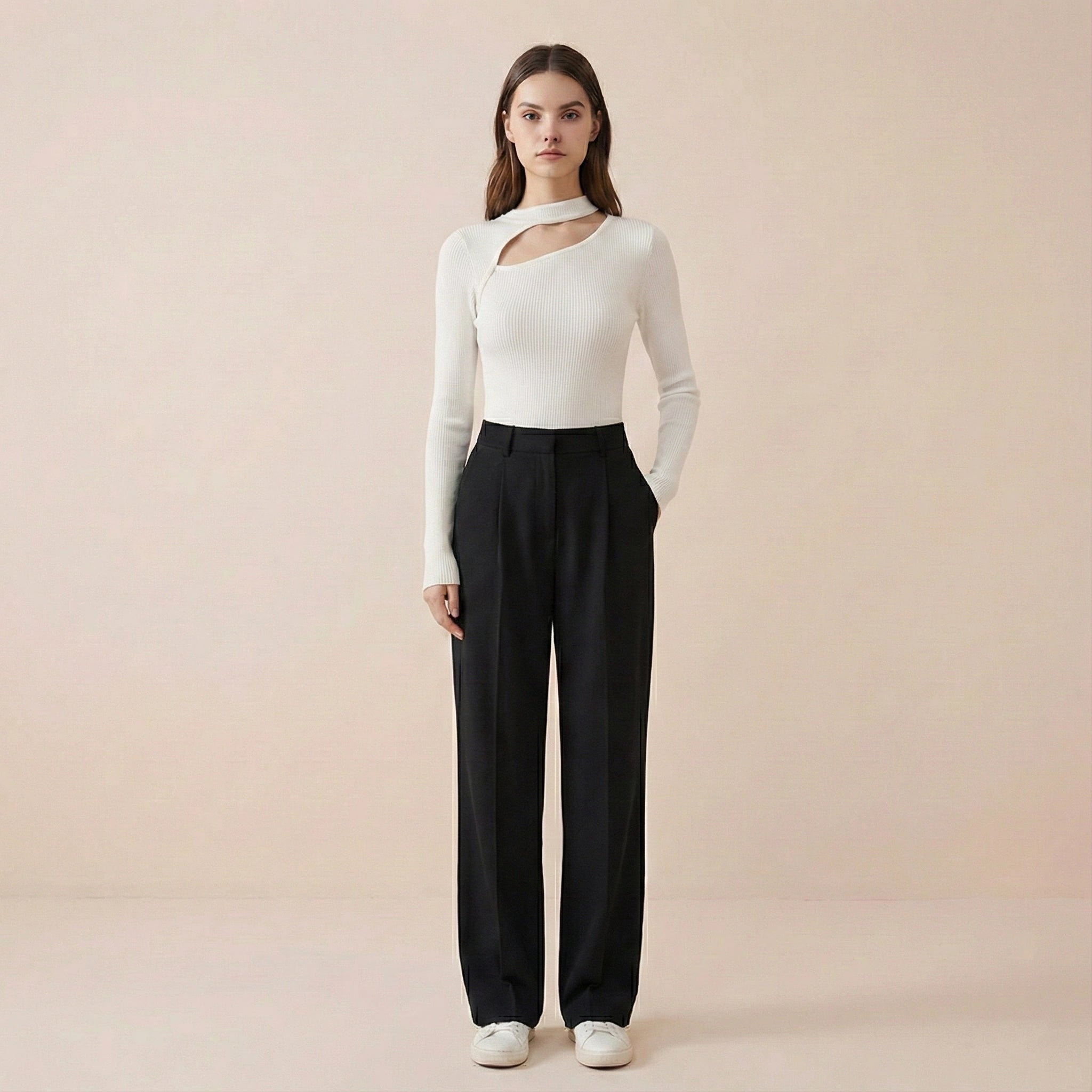 Woman wearing a white long-sleeve top and black pants on a beige background