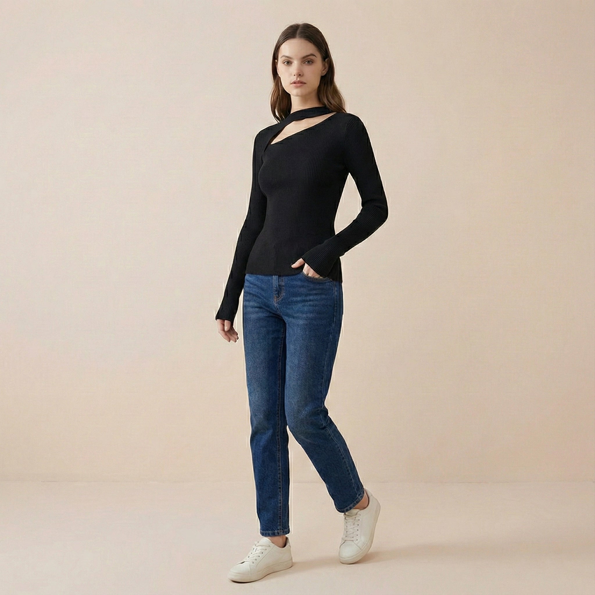 Woman wearing a black long-sleeve top and blue jeans on a beige background