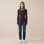 Woman wearing a brown long-sleeve top and blue jeans on a beige background