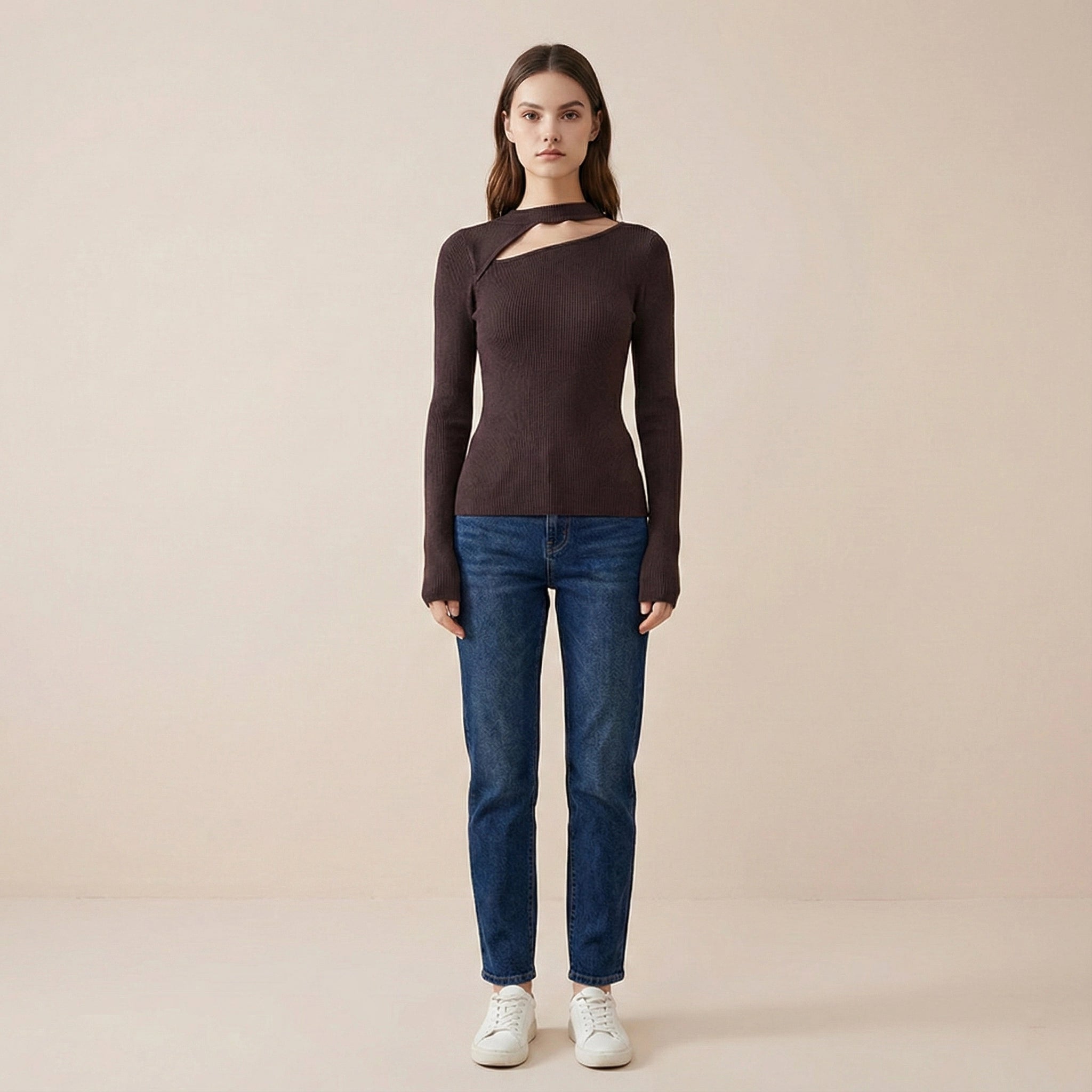 Woman wearing a brown long-sleeve top and blue jeans on a beige background