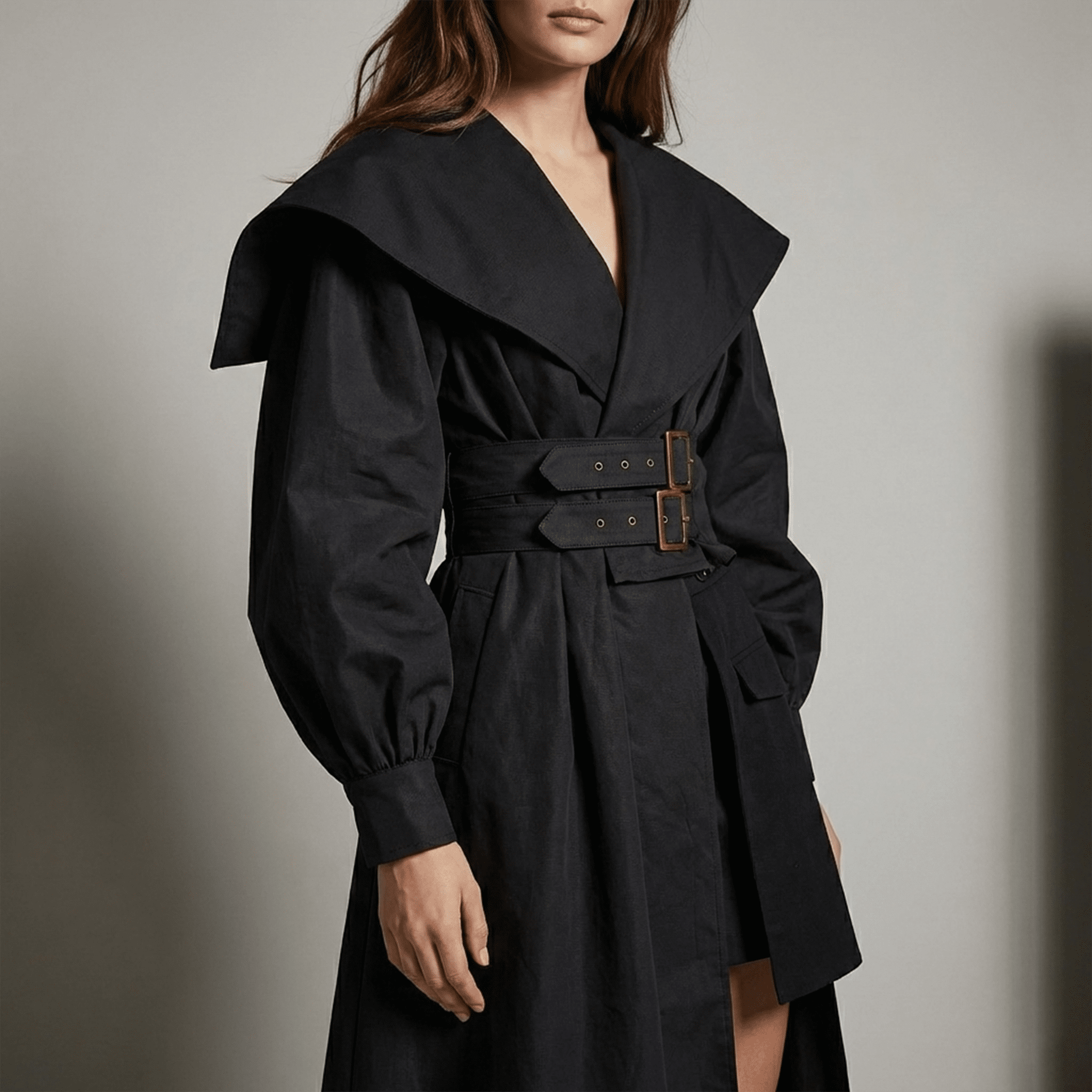 Black trench coat worn by a person on a plain background