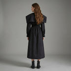 Woman wearing a black coat against a gray background