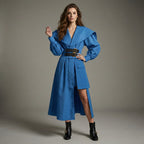 Woman wearing a blue dress with a belt against a gray background