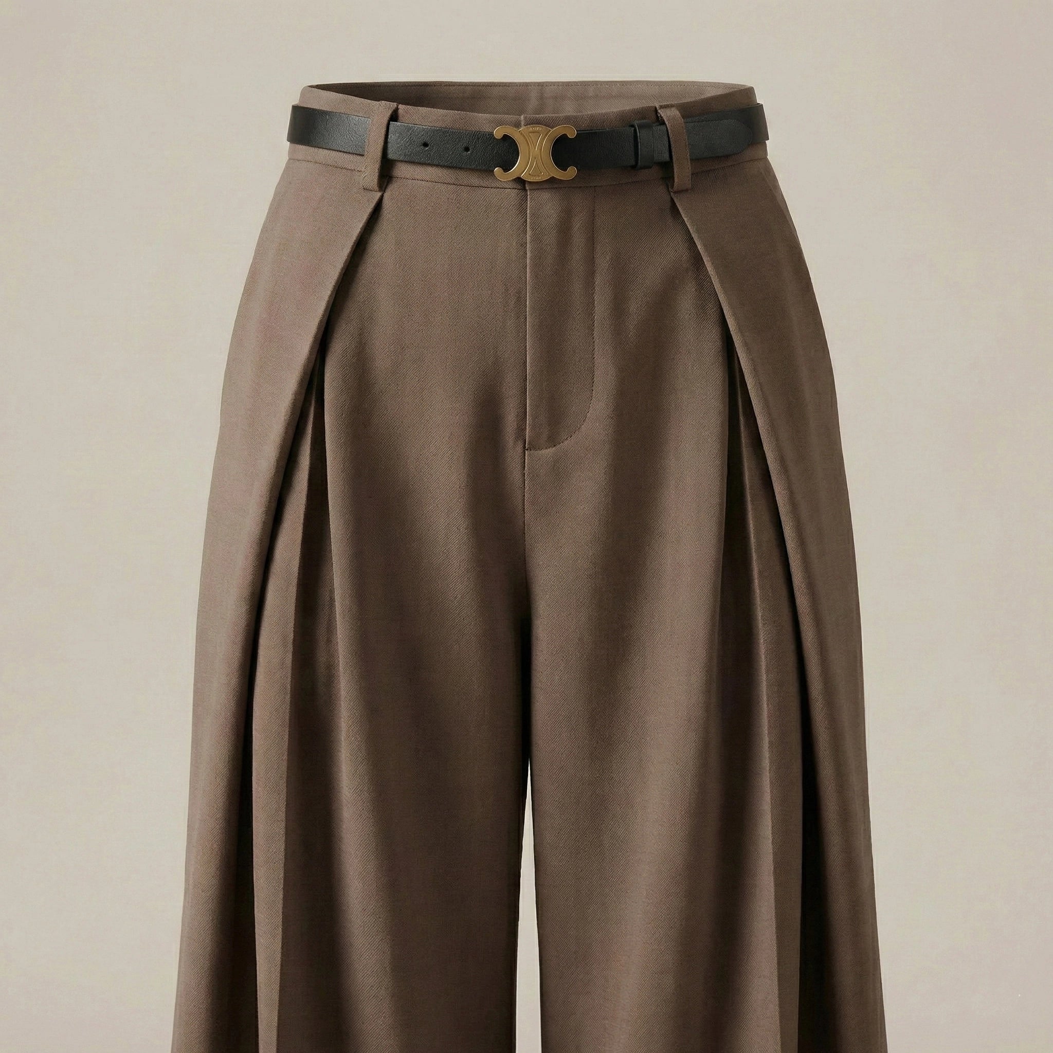 Brown pleated pants with a black belt on a beige background