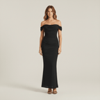 Woman wearing a black off-shoulder gown on a plain background