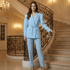 Woman in a light blue suit standing on a staircase in an elegant interior setting