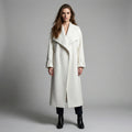Woman wearing a long white coat against a gray background