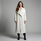 Woman wearing a long white coat against a gray background