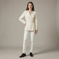 Woman wearing a cream-colored suit with a plain background