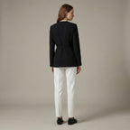 Person wearing a black blazer and white pants on a beige background
