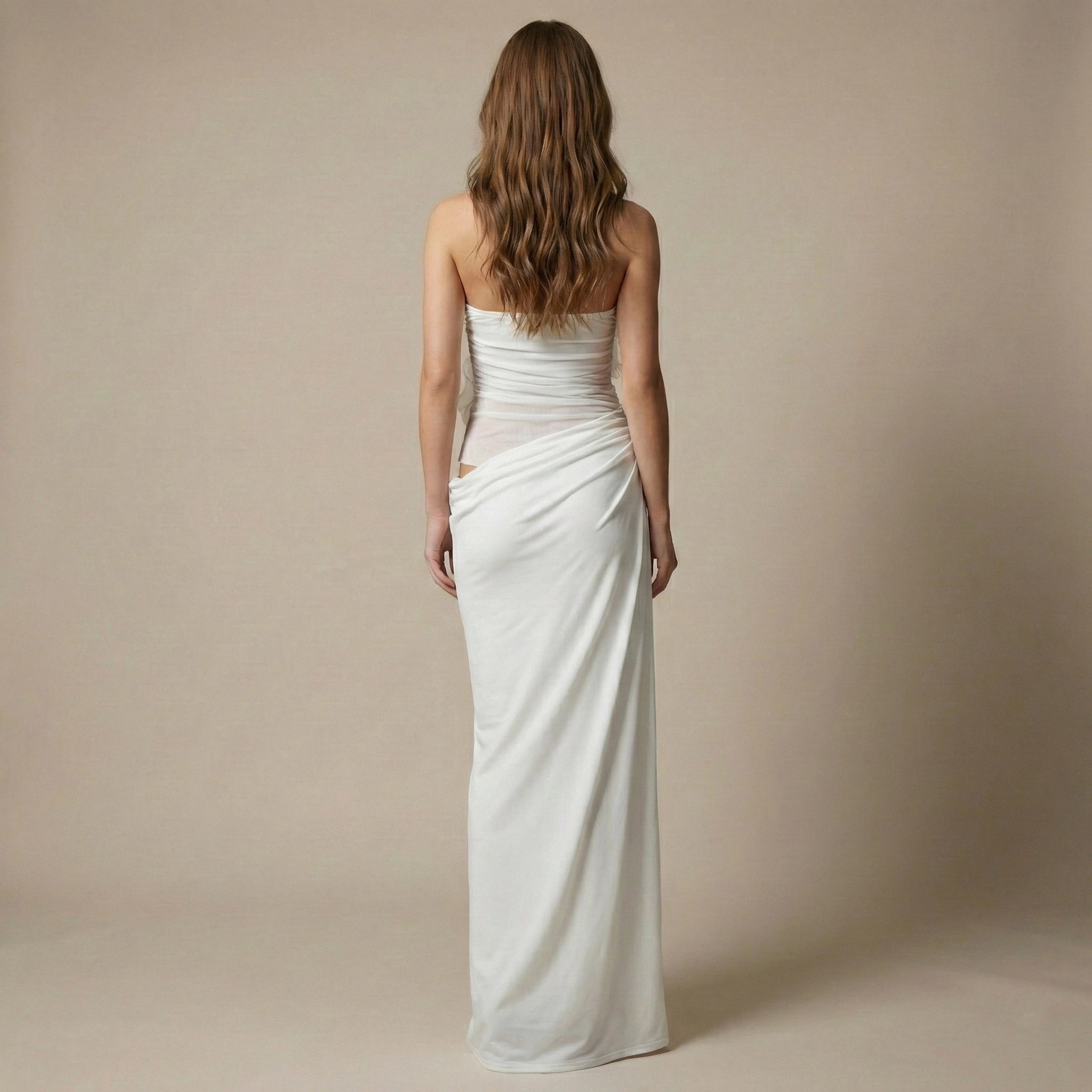 Woman wearing a strapless white gown against a beige background