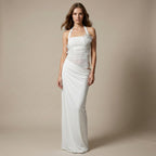 Woman wearing a white halter neck gown against a beige background