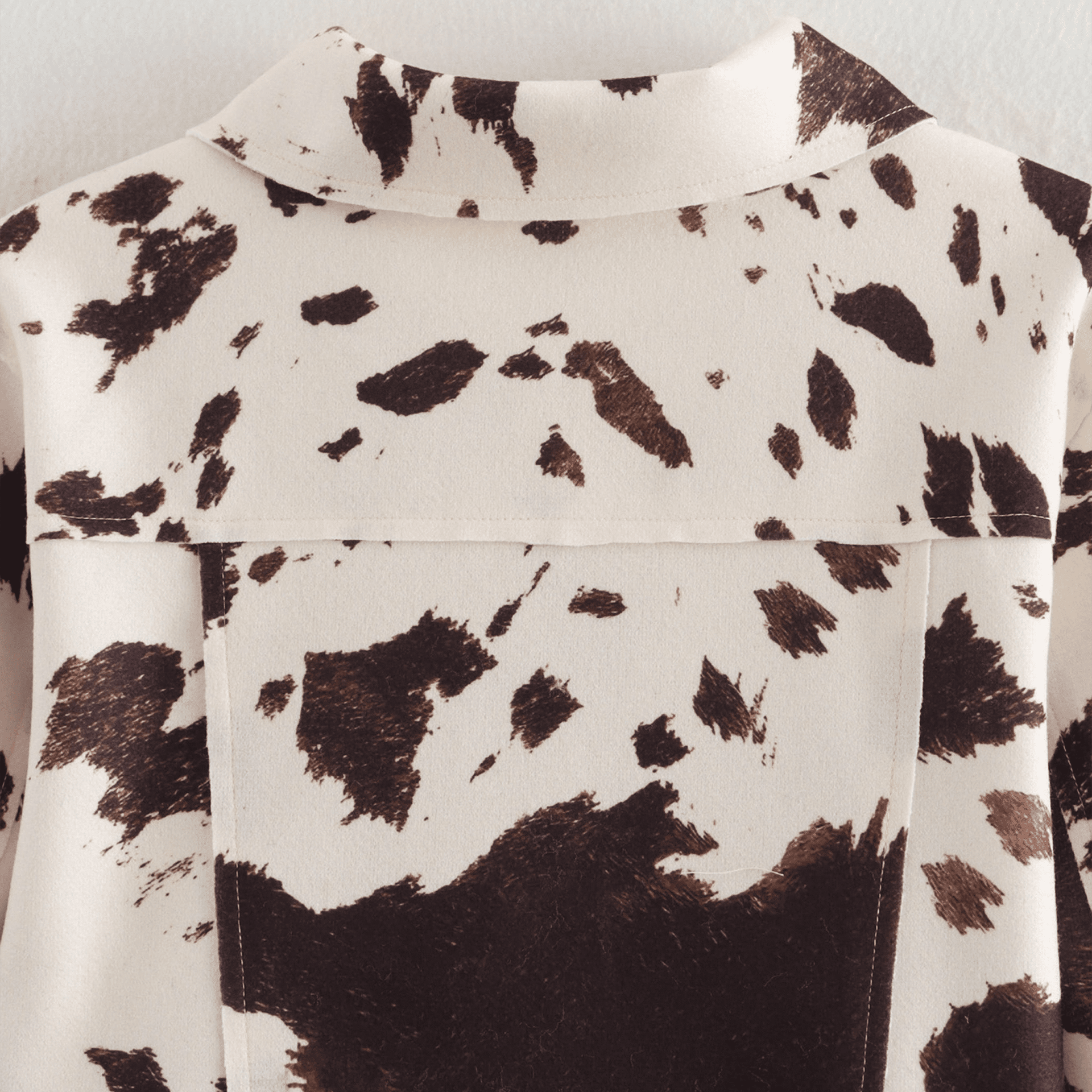 Close-up of a shirt with a cow print pattern on a plain background