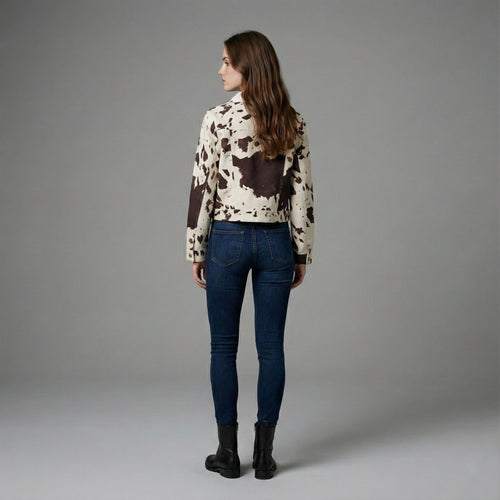 Woman wearing a cow print jacket and blue jeans on a gray background