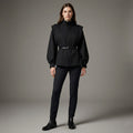Woman wearing a black outfit with a belt on a gray background