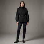 Woman wearing a black outfit with a belt on a gray background