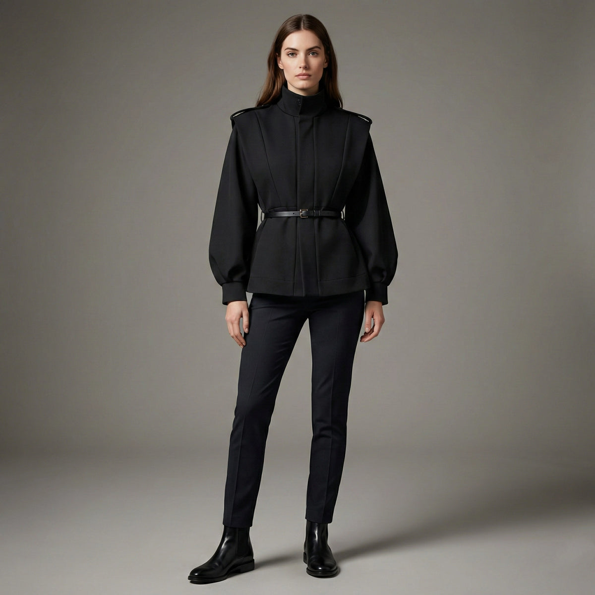 Woman wearing a black outfit with a belt on a gray background