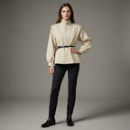 Woman wearing a beige jacket and black pants on a gray background