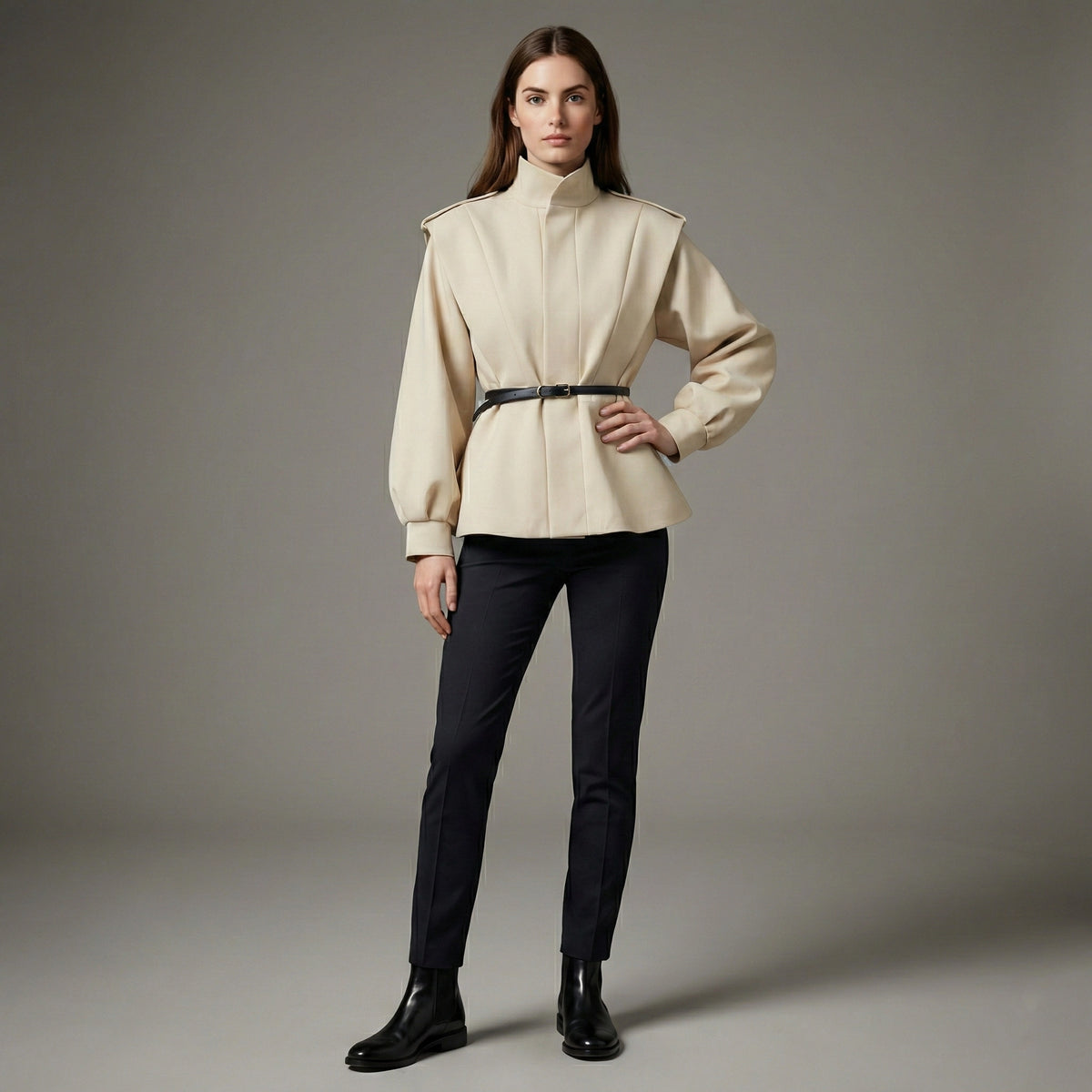 Woman wearing a beige jacket and black pants on a gray background