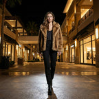 Woman in a fur coat walking through a shopping mall at night.
