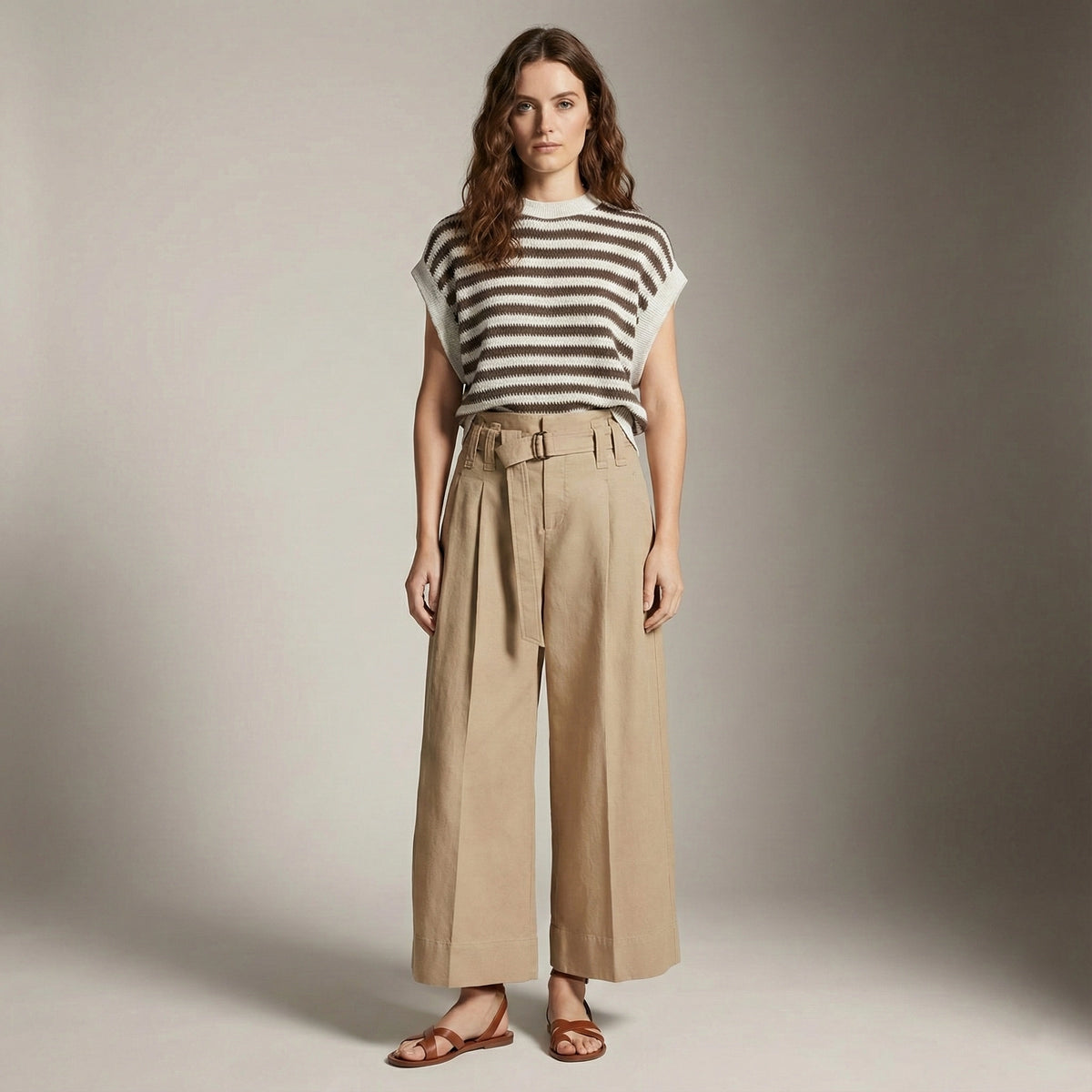 Woman wearing a striped shirt and beige pants against a plain background