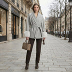 Woman in a gray coat with fur trim walking on a city street.