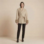 Woman wearing a beige coat with fur trim on a beige background