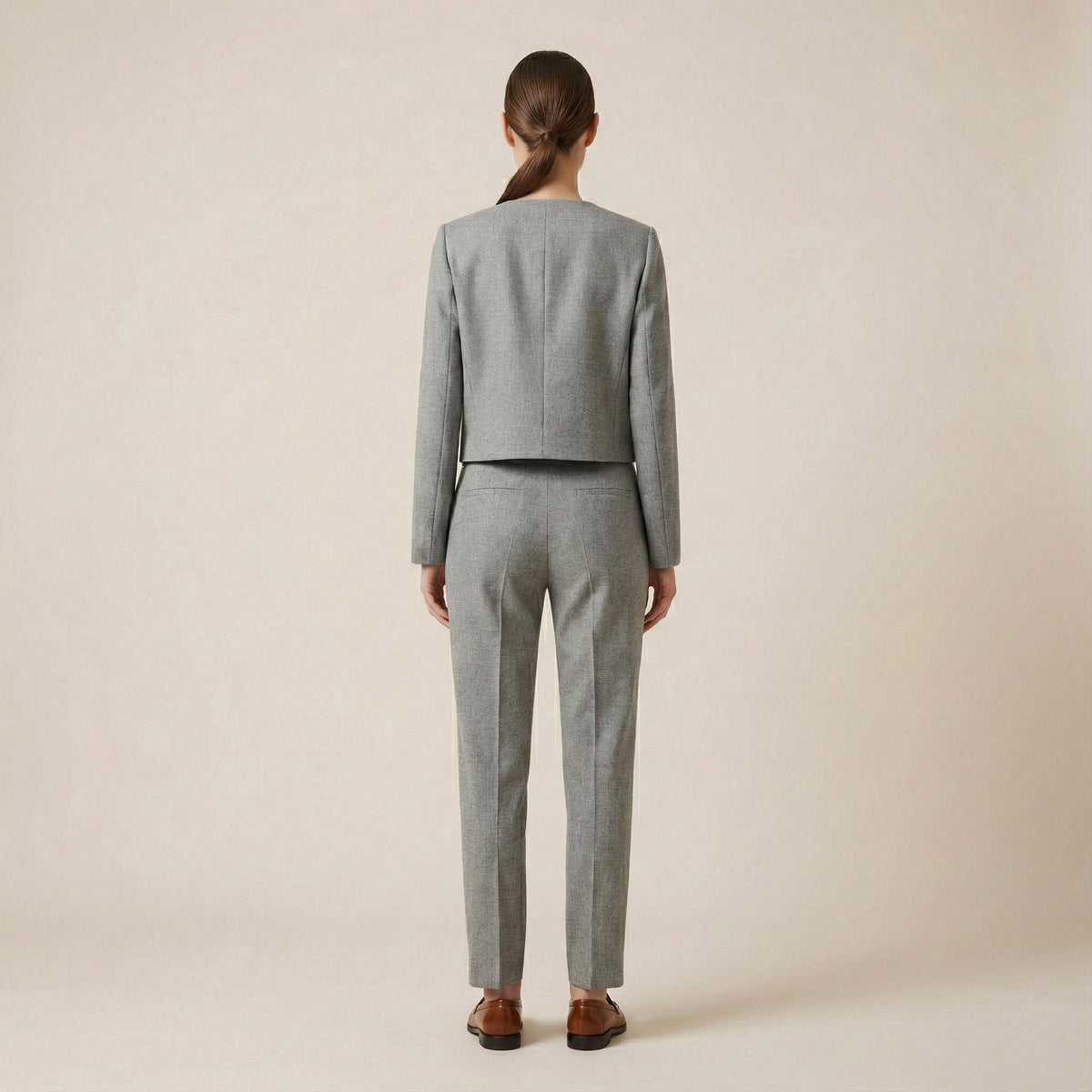 Person wearing a gray suit on a beige background