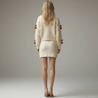 Woman wearing a cream-colored outfit with red accents on a plain background