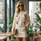 Woman wearing a cream-colored outfit with cherry details in an urban setting.