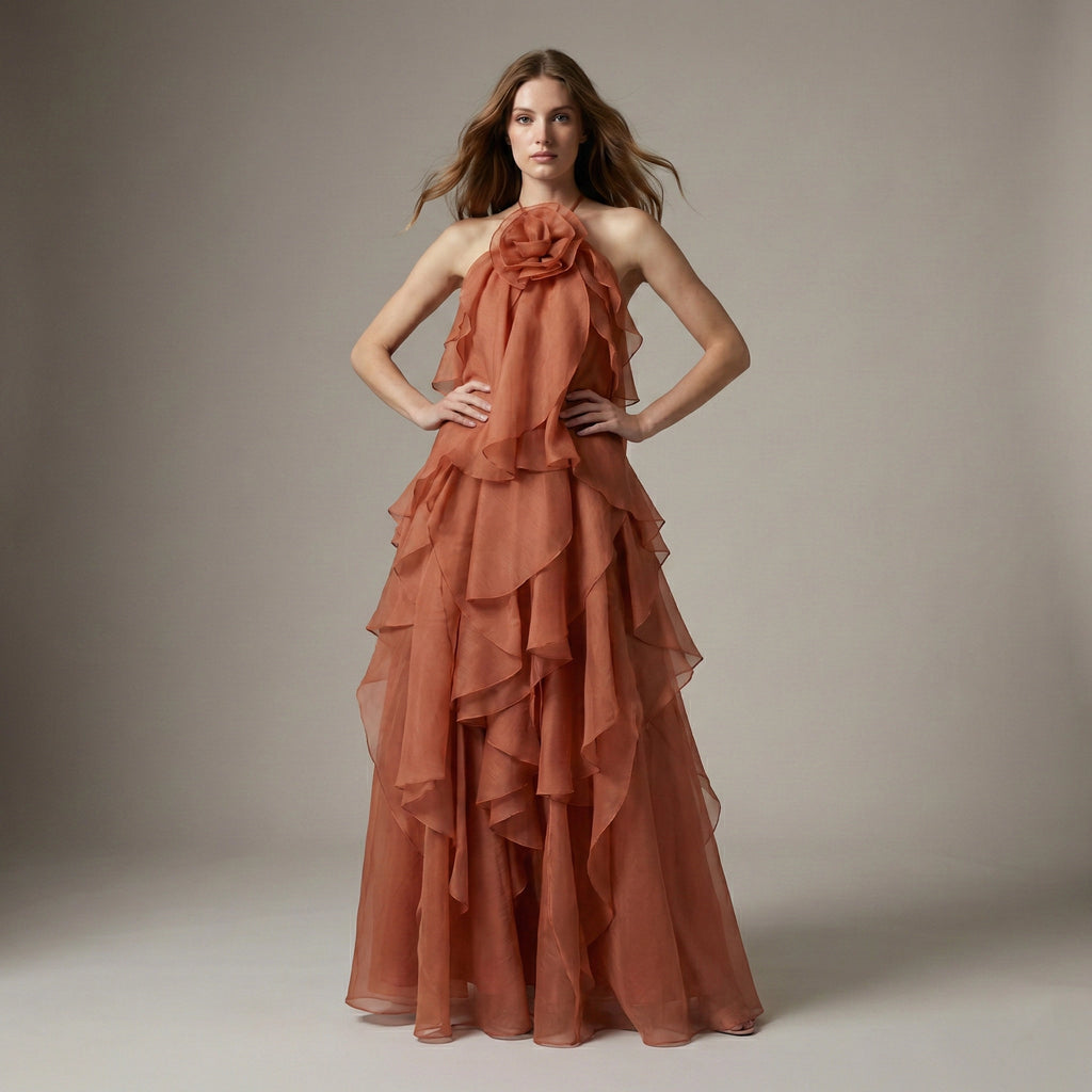 Woman wearing a rust-colored, ruffled gown against a neutral background