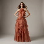 Woman wearing a rust-colored, ruffled gown against a neutral background